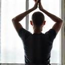 Person performing a quick, energizing stretch by a window.